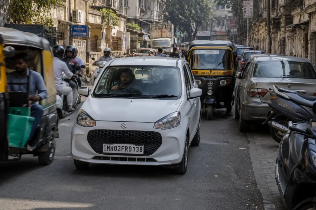 Small hatchback driving through crowded Indian city traffic